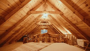 An attic bedroom with wooden beams, a bed, and a window.