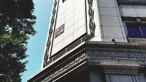 Fachada de edificio con un gran cartel ornamentado con escritura árabe.
