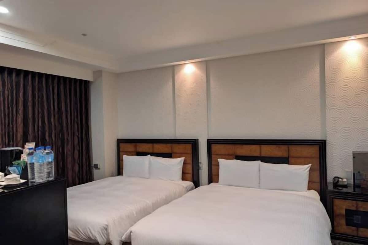 Habitación de hotel con dos camas, un minibar y una cortina.