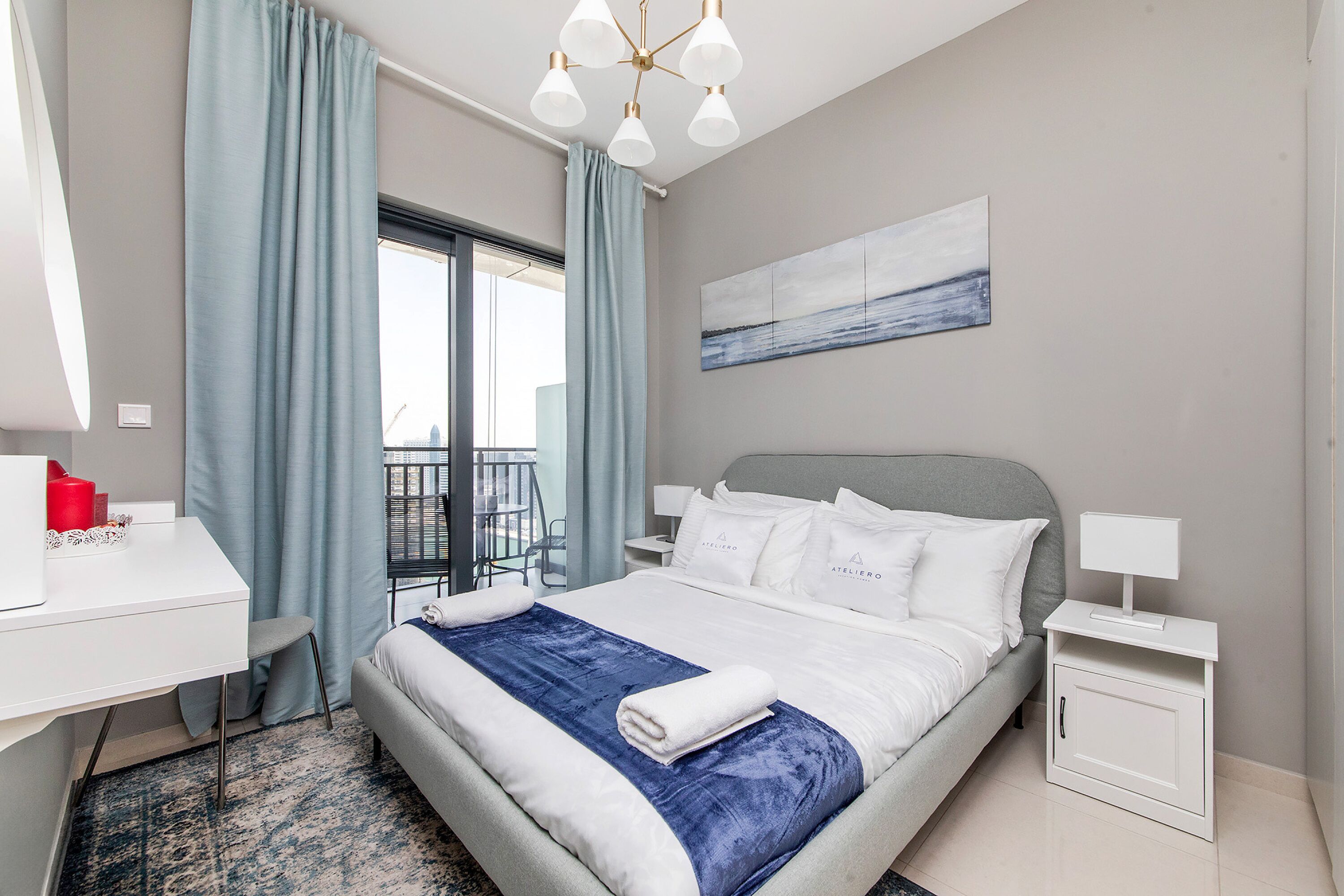 A modern hotel room with a large bed, a desk, and a view of the city.
