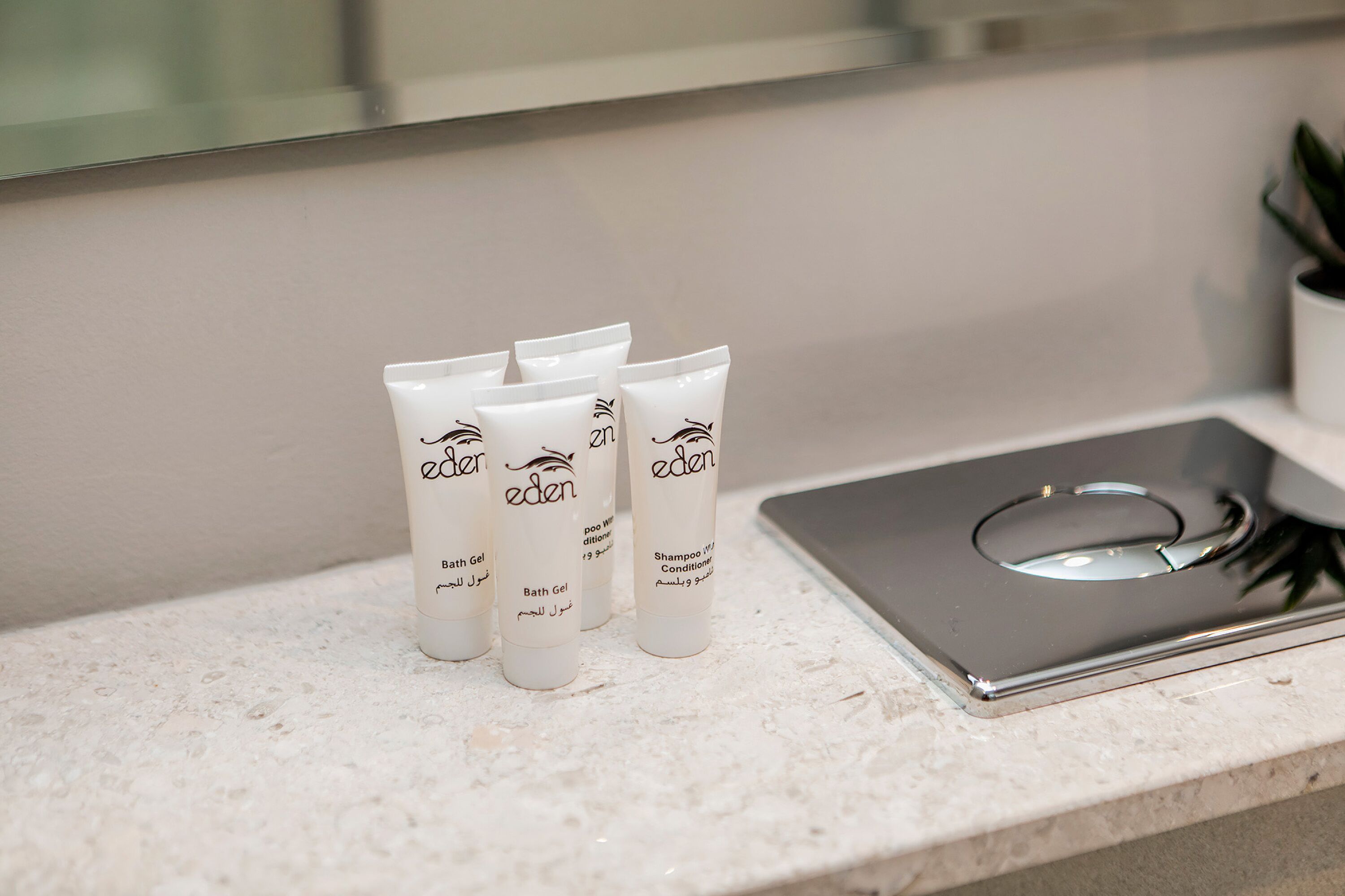 A bathroom counter with three Eden bath gels and a silver tray.