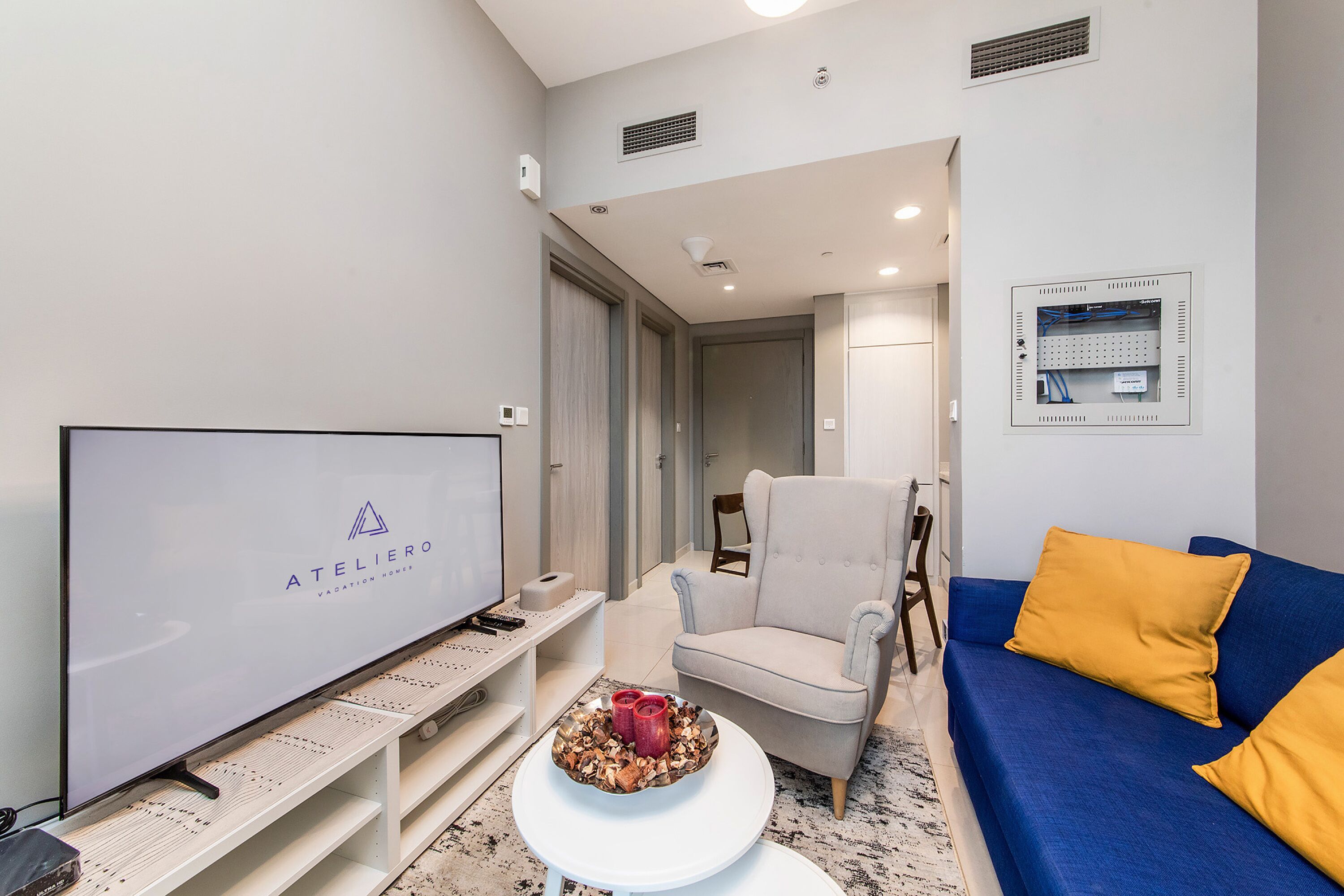 Un salon moderne avec un téléviseur à écran plat, un canapé, un fauteuil et une table basse.
