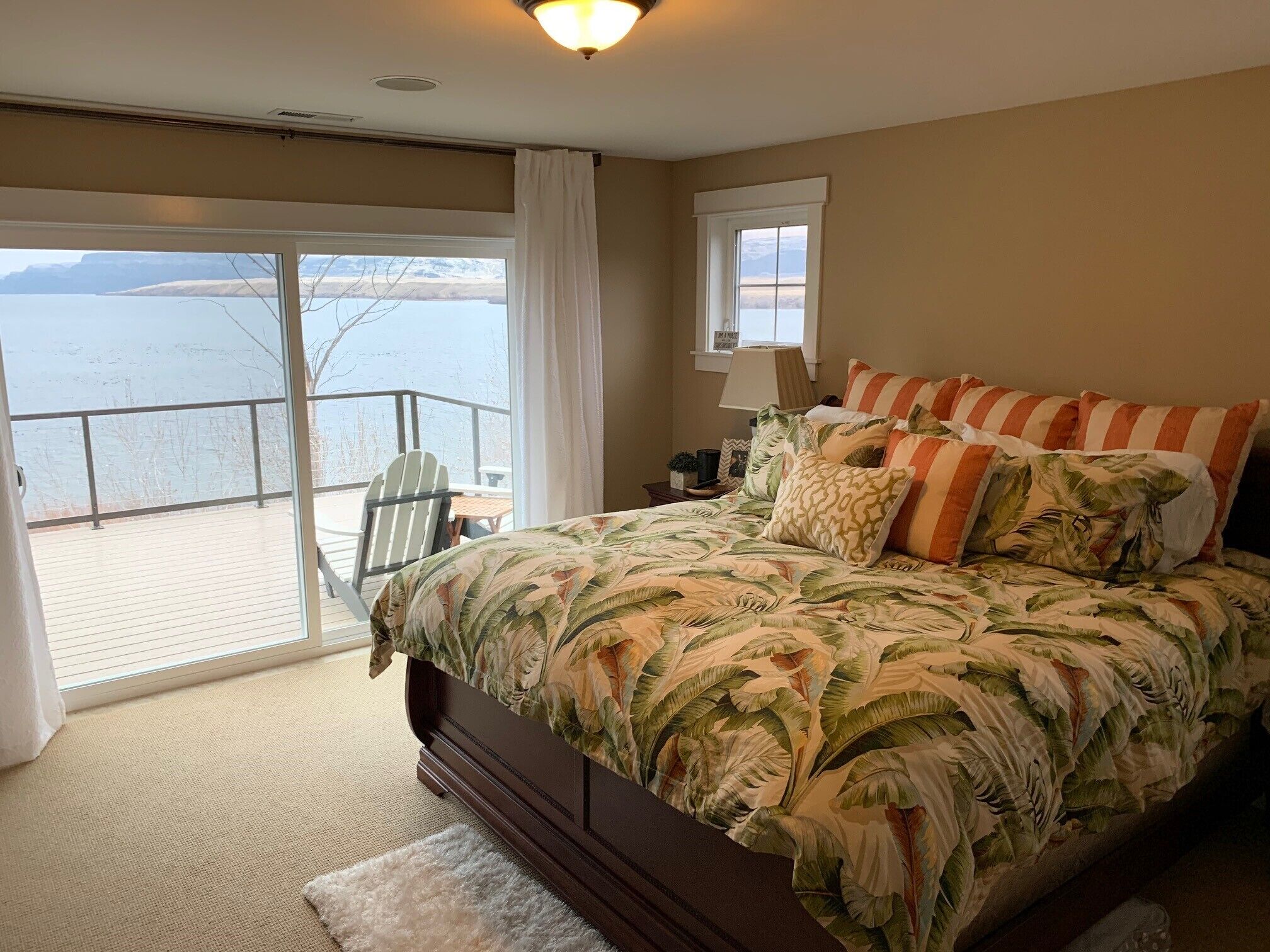 A bedroom with a large bed, a view of the water, and a balcony.