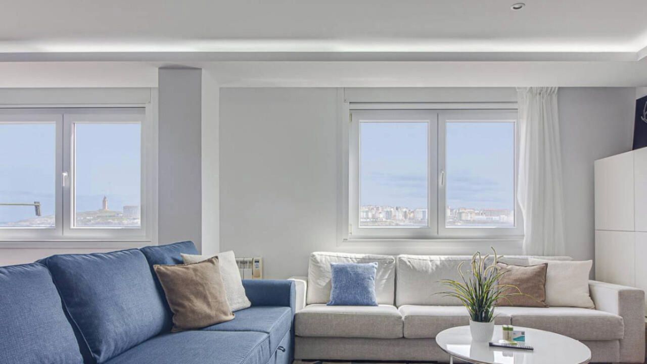 A modern living room with a blue sofa, a beige sofa, and a white coffee table.