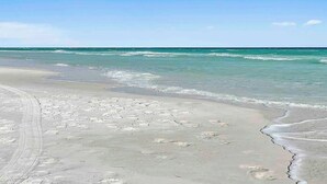 Una playa con arena y olas acercándose a la orilla.