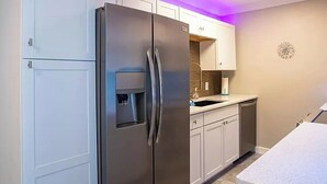 Una cocina moderna con armarios blancos, un refrigerador de acero inoxidable y un lavamanos empotrado.