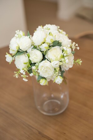 Un bouquet de fleurs blanches dans un vase transparent, posé sur une table en bois.
