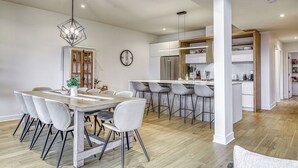 Una cocina moderna con una isla central, taburetes de bar y un comedor con una mesa y sillas de madera.