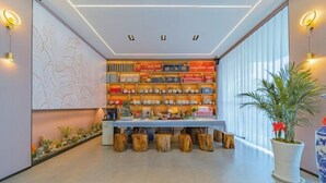 A modern reception area with a wooden bench, a plant, and a wall of neatly arranged items. - Dali Teng'ange Smart Hotel (Dali High-speed Railway Station) (Dali City)