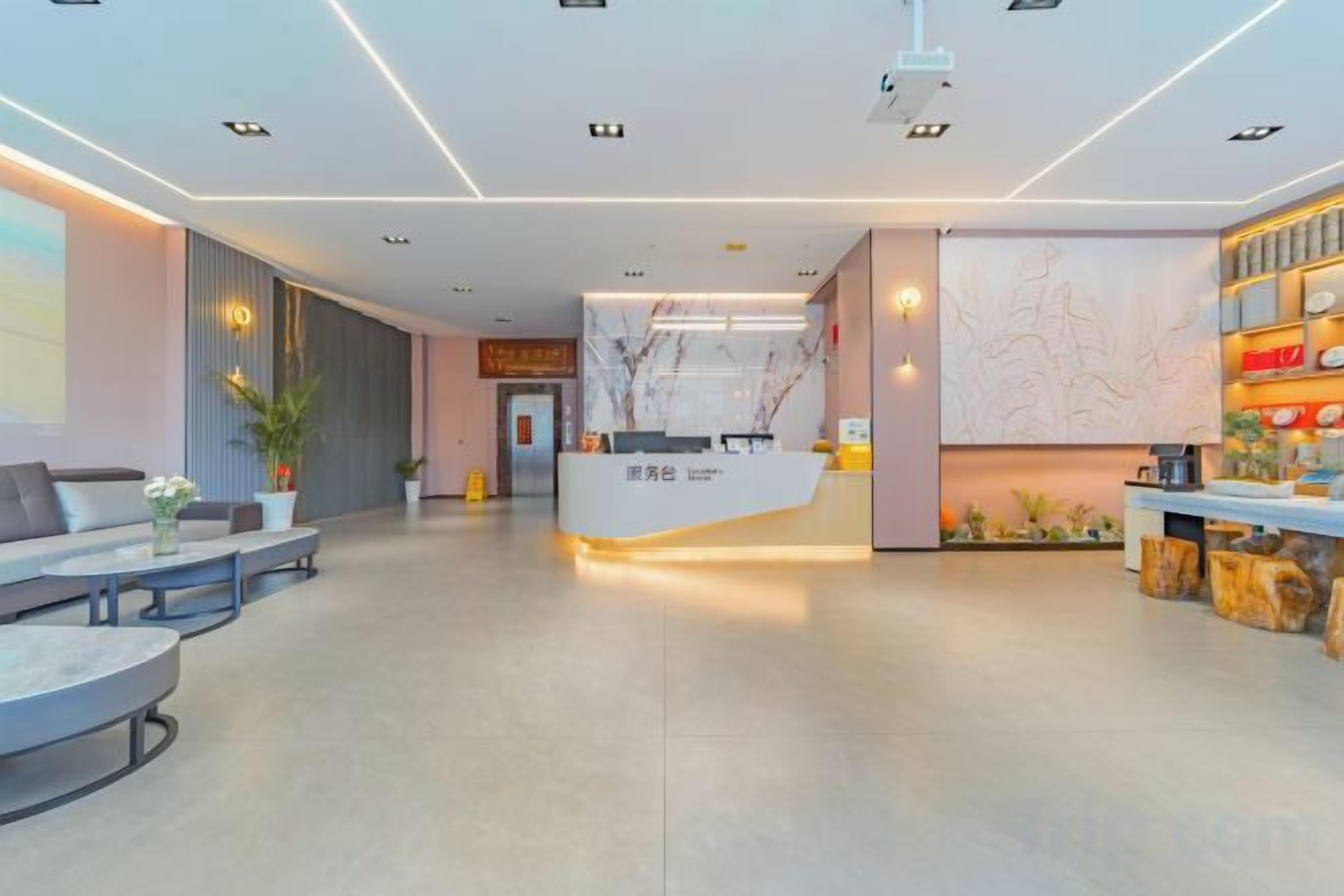 A modern hotel lobby with a reception desk, seating area, and a wall with a decorative design.