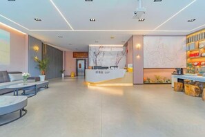A modern hotel lobby with a reception desk, seating area, and a wall with a decorative design. - Dali Teng'ange Smart Hotel (Dali High-speed Railway Station) (Dali City)