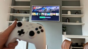 A living room with a TV displaying Xbox games, a white game controller, and shelves with decorative items. - Stylish Kennington flat w/garden, KING bed nr tube (Greater London)