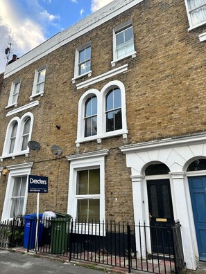 A two-story brick building with white-framed windows, a blue door, and a sign for 'Dexters.'