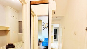A narrow hallway leading to a bedroom with a bed, a small table, and a blue chair. - Stylish Kennington flat w/garden, KING bed nr tube (Greater London)