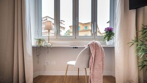 A room with a large window, a white chair, and a potted plant. - Cozy apartment with terrace suitable for families up to 6 people  (Roma)