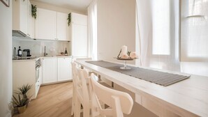 A modern kitchen with white cabinetry, a wooden countertop, and a dining area with white chairs. - Cozy apartment with terrace suitable for families up to 6 people  (Roma)