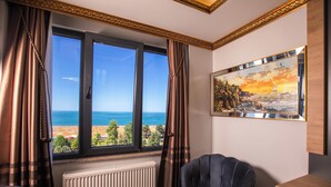Una habitación con un ventanal grande que ofrece vistas al mar, un cuadro en la pared y un radiador debajo.