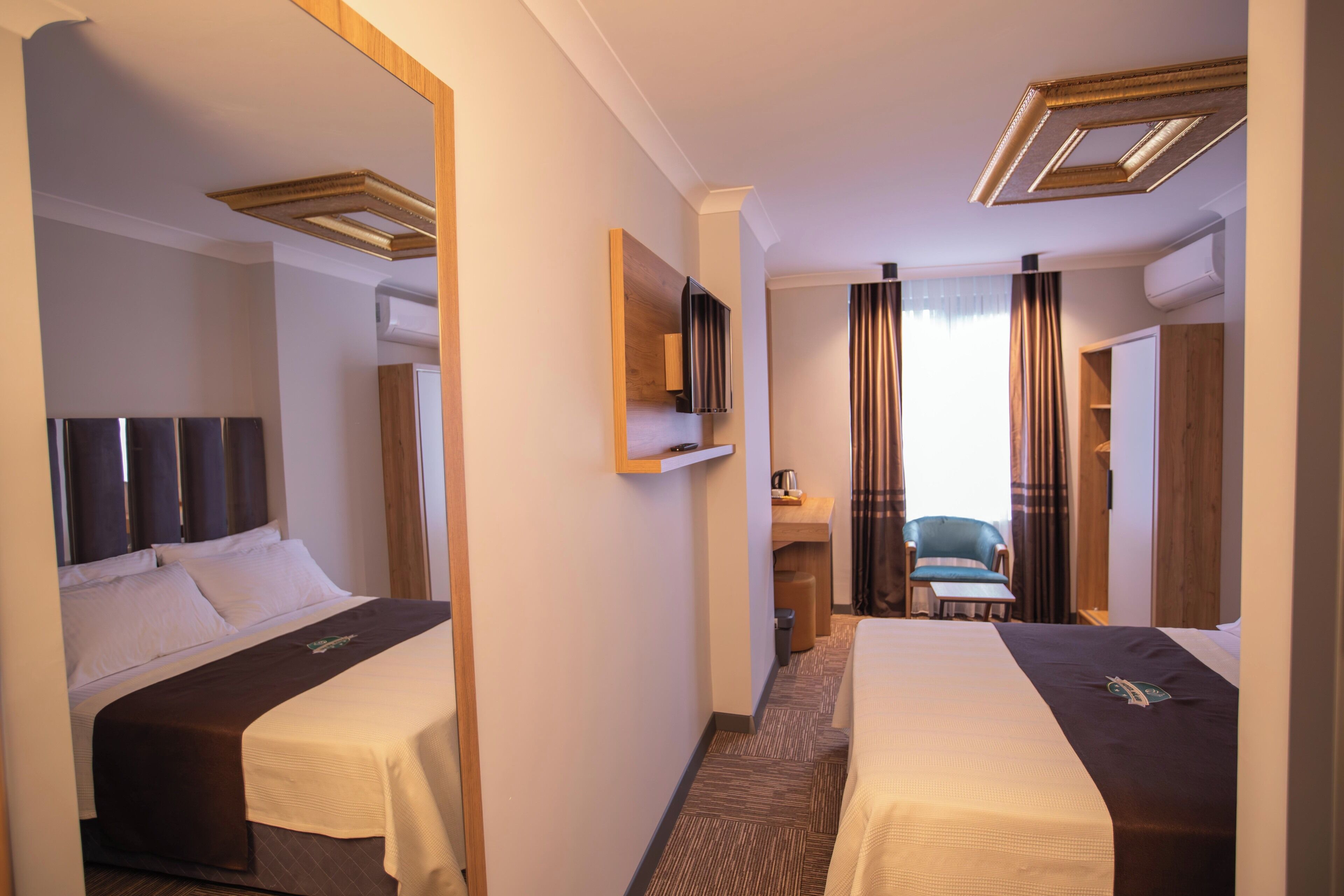 Ein Hotelzimmer mit zwei Betten, einem Schreibtisch, einem Stuhl und einem Fernseher.