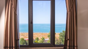 Una ventana con vista al mar y a la costa rocosa.