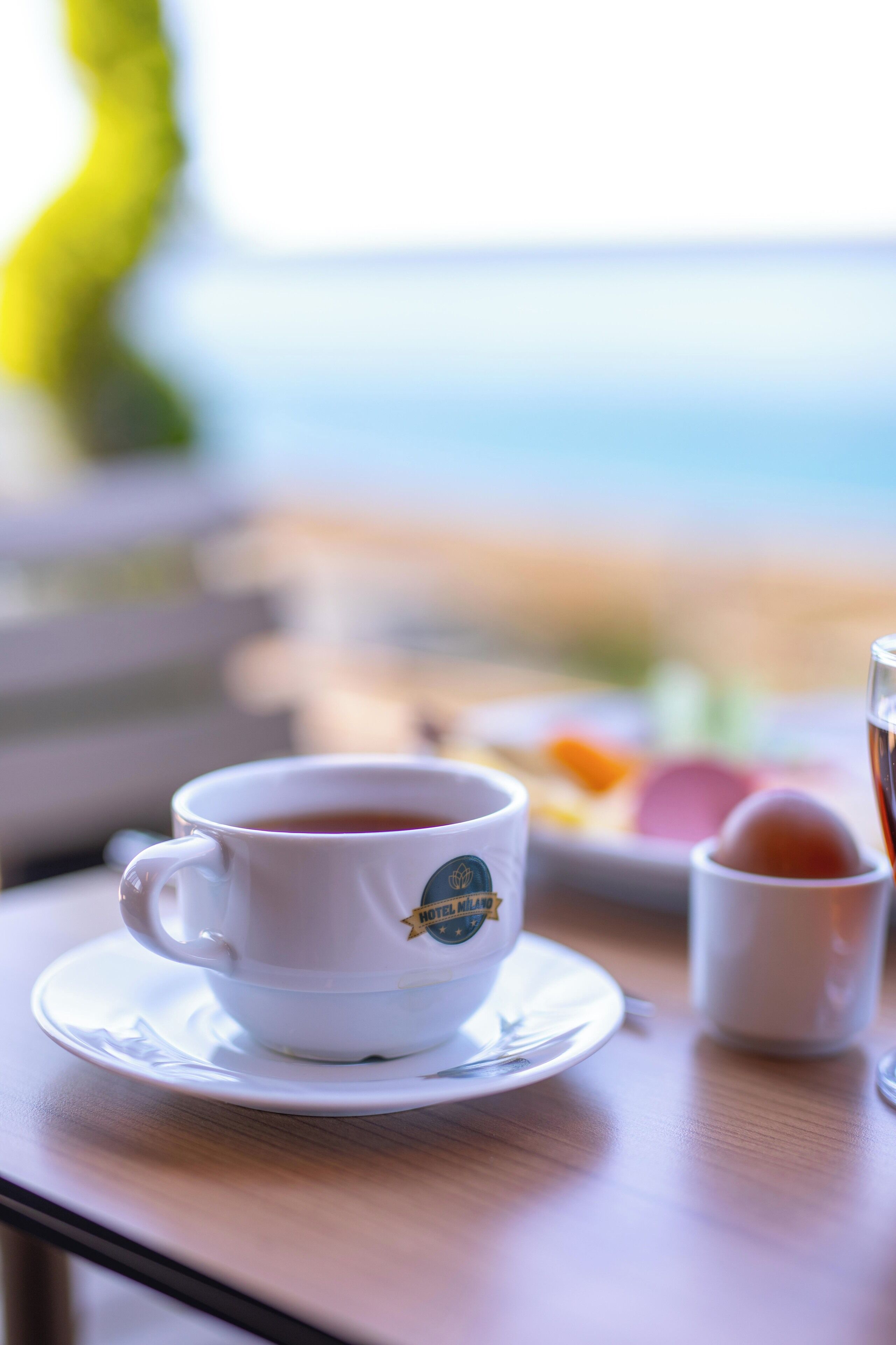 A cup of coffee on a table with a view of the sea in the background.