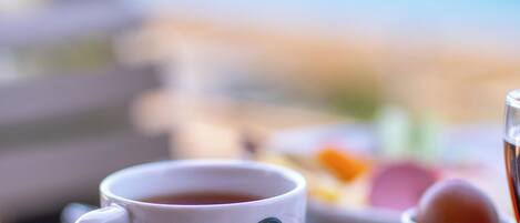 A cup of coffee on a table with a view of the sea in the background.