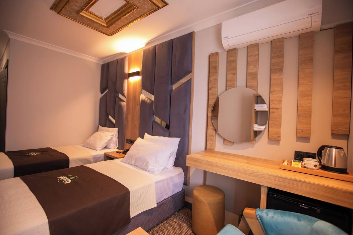 A hotel room with two beds, a desk, a chair, and a mirror.