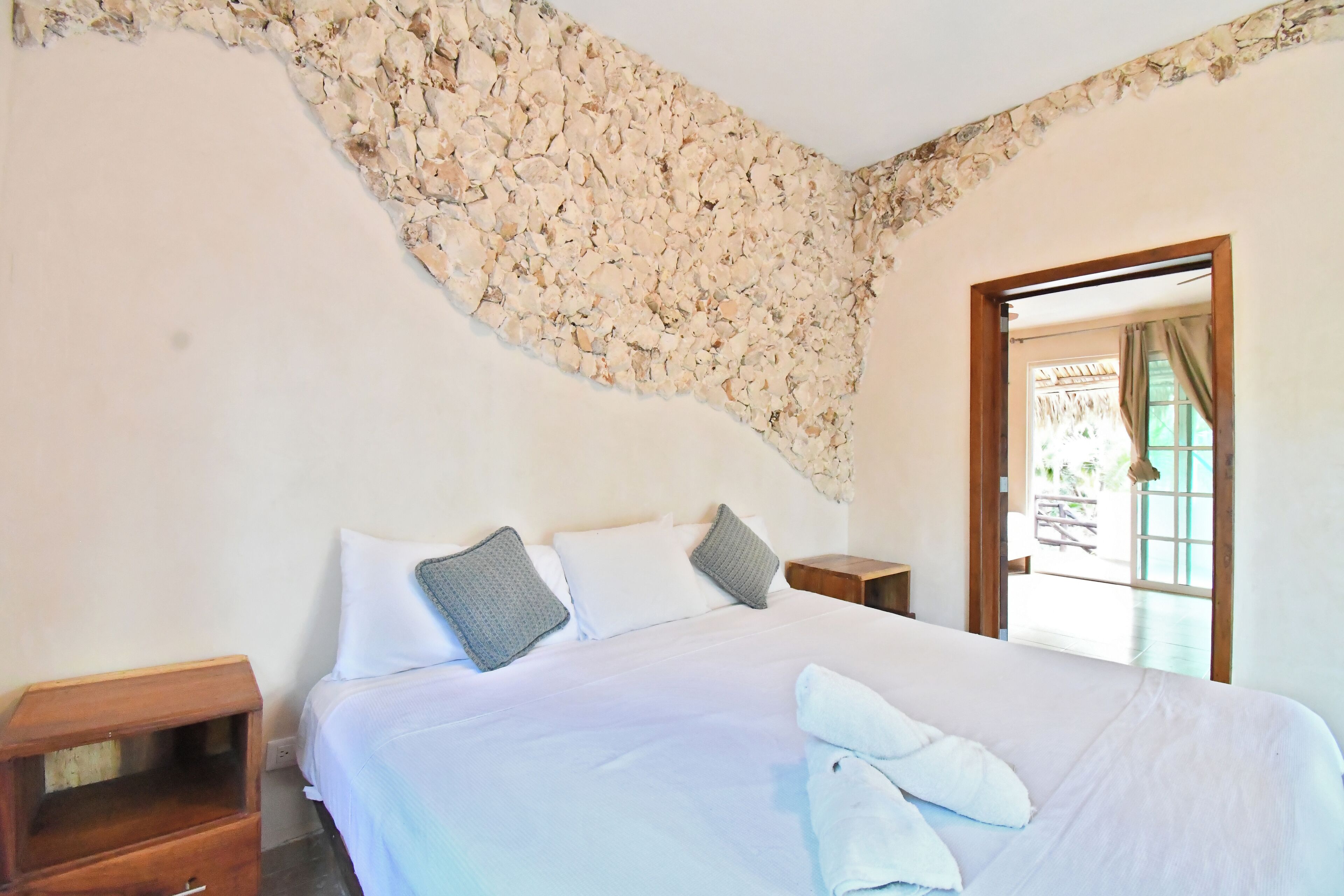 Un dormitorio con una cama grande, dos mesitas de noche y vistas al exterior a través de una puerta.