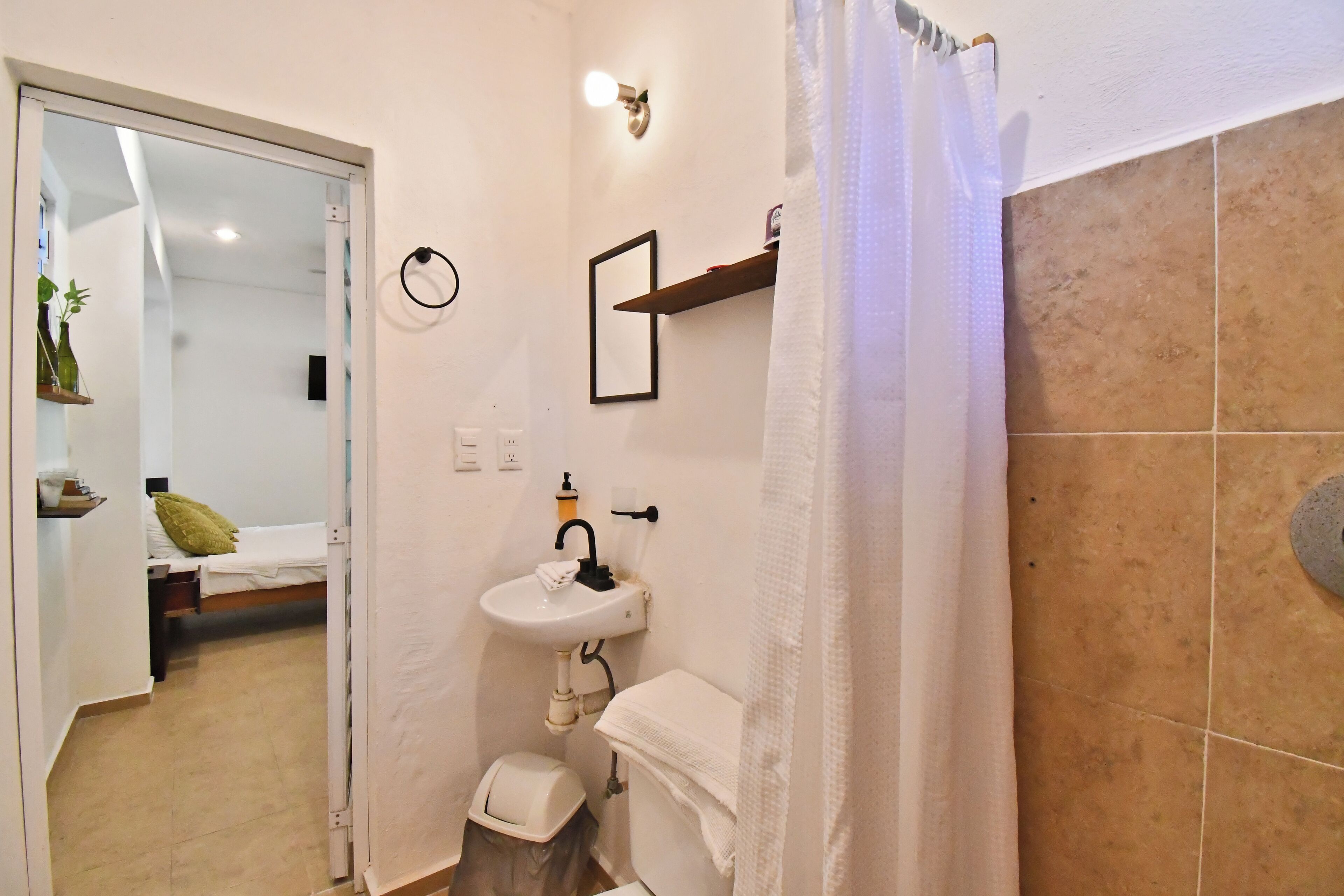 Un baño pequeño con lavamanos, inodoro y cortina de ducha.