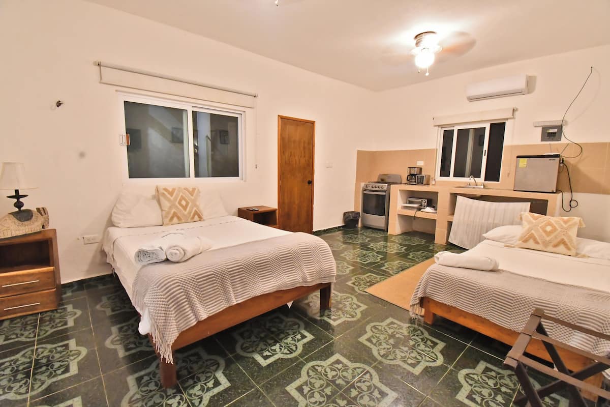 Habitación de hotel con dos camas, kitchenette y baño.