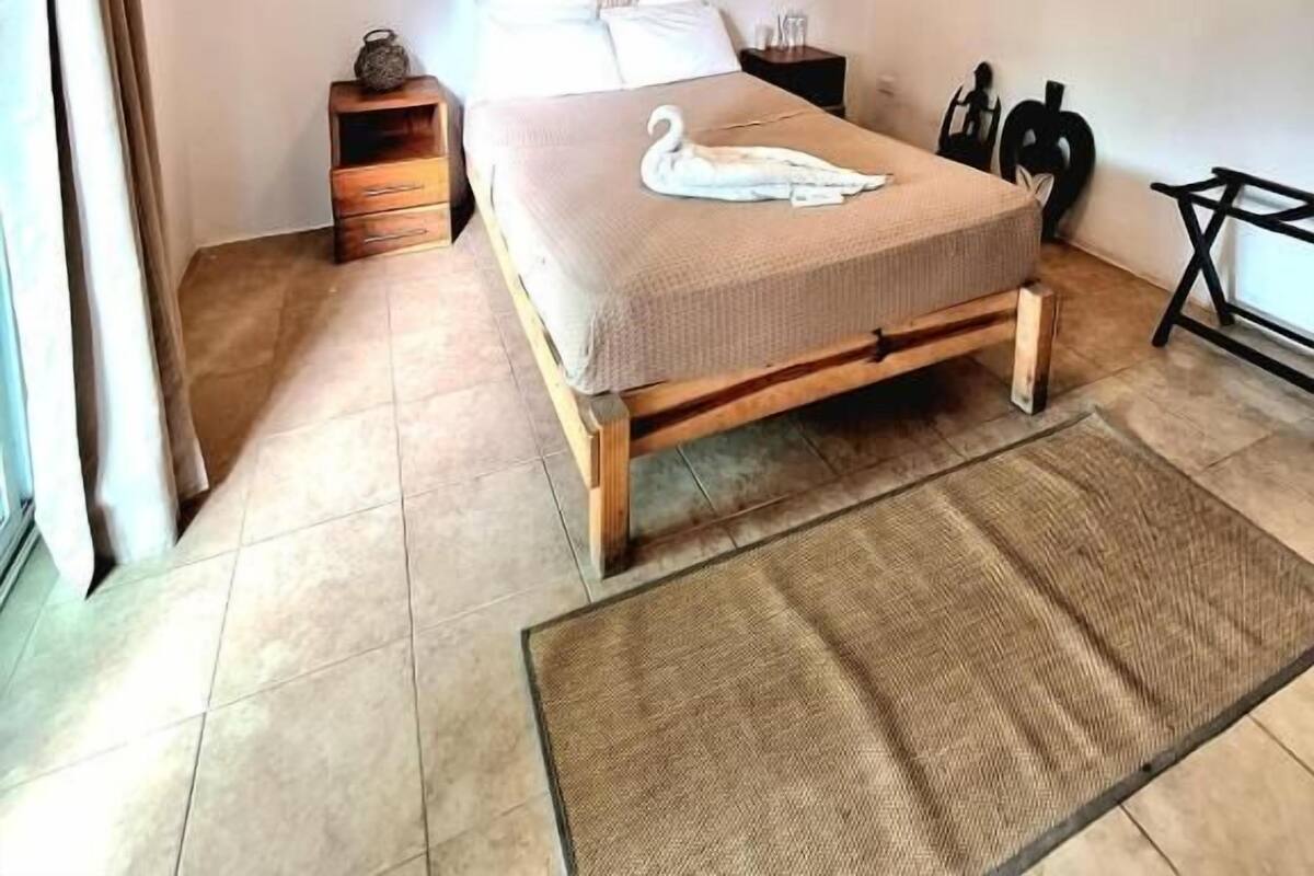 Un dormitorio con cama, ventilador de techo, tabla de remo fijada a la pared, mesita de noche pequeña y mesita auxiliar.