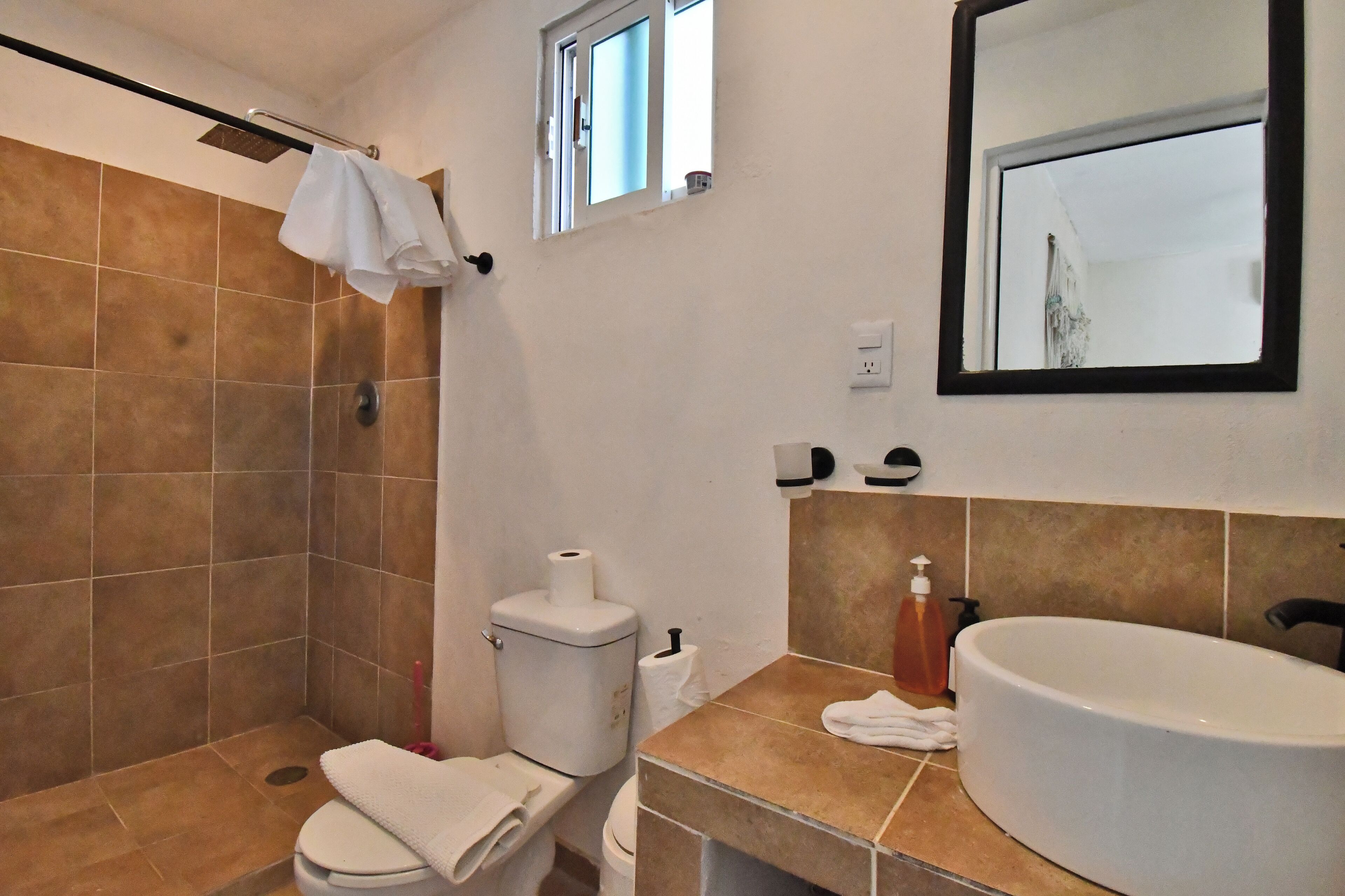 A bathroom with a shower, toilet, sink, and a mirror.