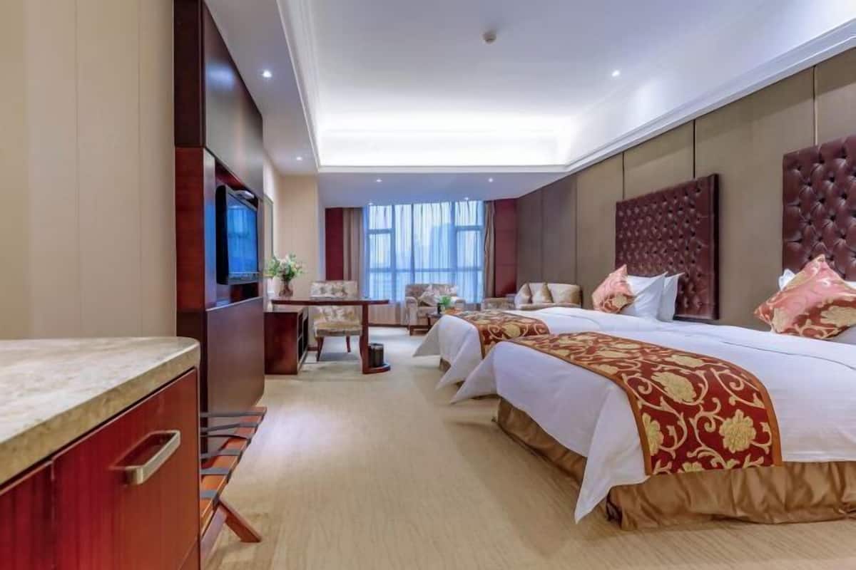 A hotel room with a large bed, a desk, a television, and a view of the outdoors.