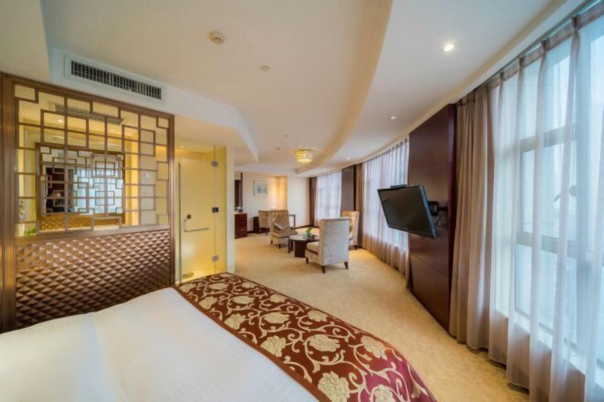 A hotel room with a bed, a TV, a desk, and a chair.