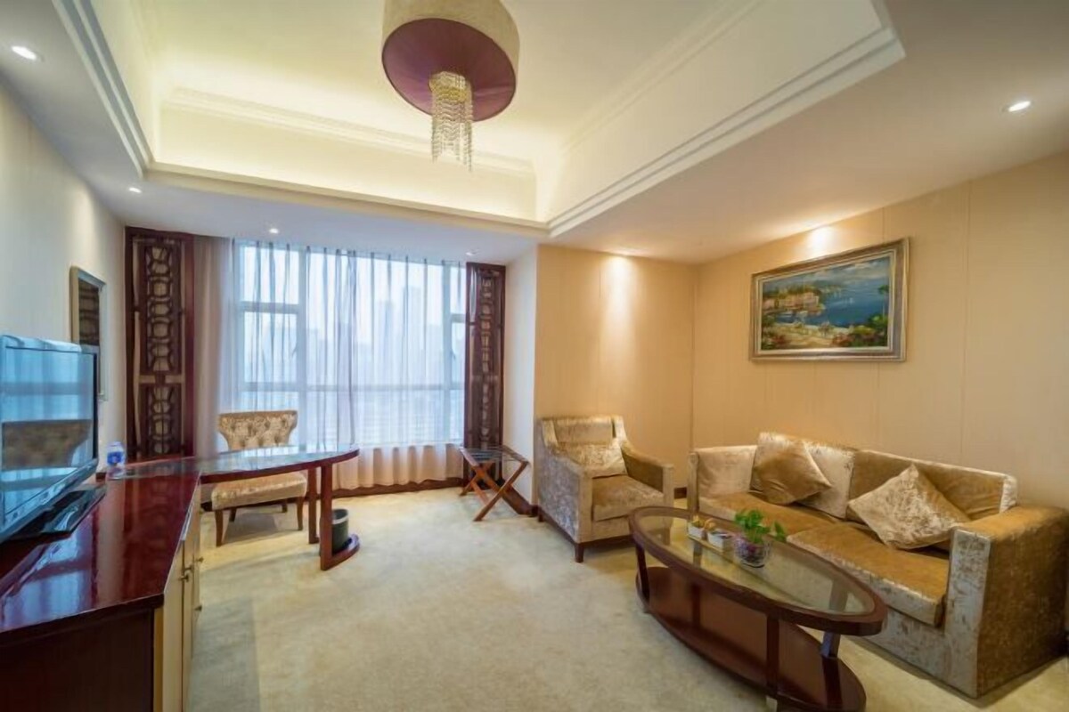 A living room with a sofa, armchairs, a coffee table, a TV, and a painting on the wall.