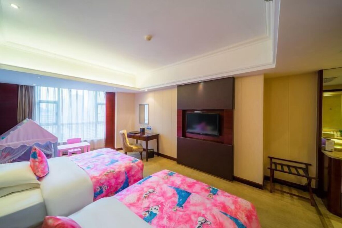 A hotel room with two beds, a TV, a desk, and a chair.