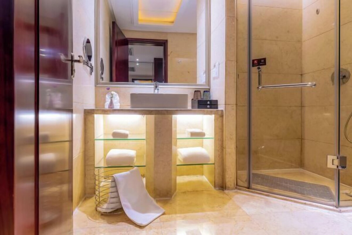 A modern bathroom with a glass shower enclosure, a vanity with a glass shelf, and a mirror.