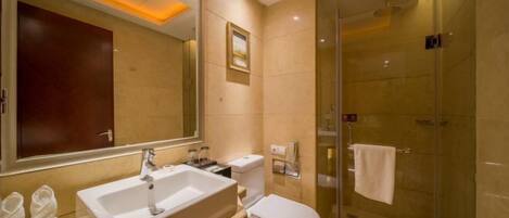 A modern bathroom with a large mirror, a sink, a toilet, and a glass-enclosed shower.