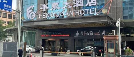 A hotel entrance with a sign reading 'FENGQIAN HOTEL' and a visible entrance gate.
