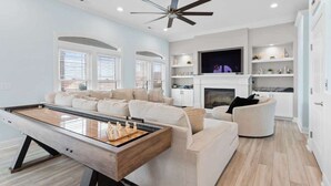 A modern living room with a pool table, a fireplace, and a television. - Beach Access (Ocean Isle Beach)