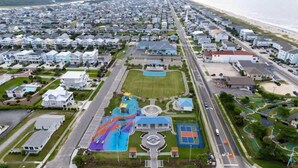 An aerial view of a residential area with houses, a road, and a playground with slides and a basketball court. - Beach Access (Ocean Isle Beach)