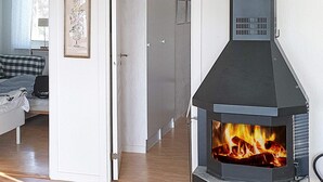 Una sala de estar moderna con una estufa de leña, un sofá a cuadros y un cuadro enmarcado en la pared.