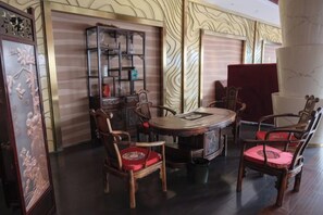 Un comedor tradicional con una mesa redonda y sillas de madera, un aparador decorativo y un papel tapiz estampado.