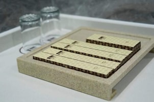 Una plataforma de piedra con cuatro objetos rectangulares, posiblemente equipaje o elementos de almacenamiento, sobre una superficie blanca.