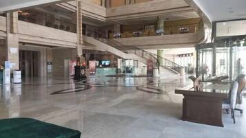 A spacious lobby with a central staircase, a reception desk, and a seating area.