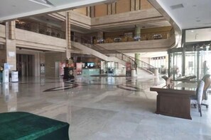 Un hall amplio con una escalera central, una recepción y una zona de estar.