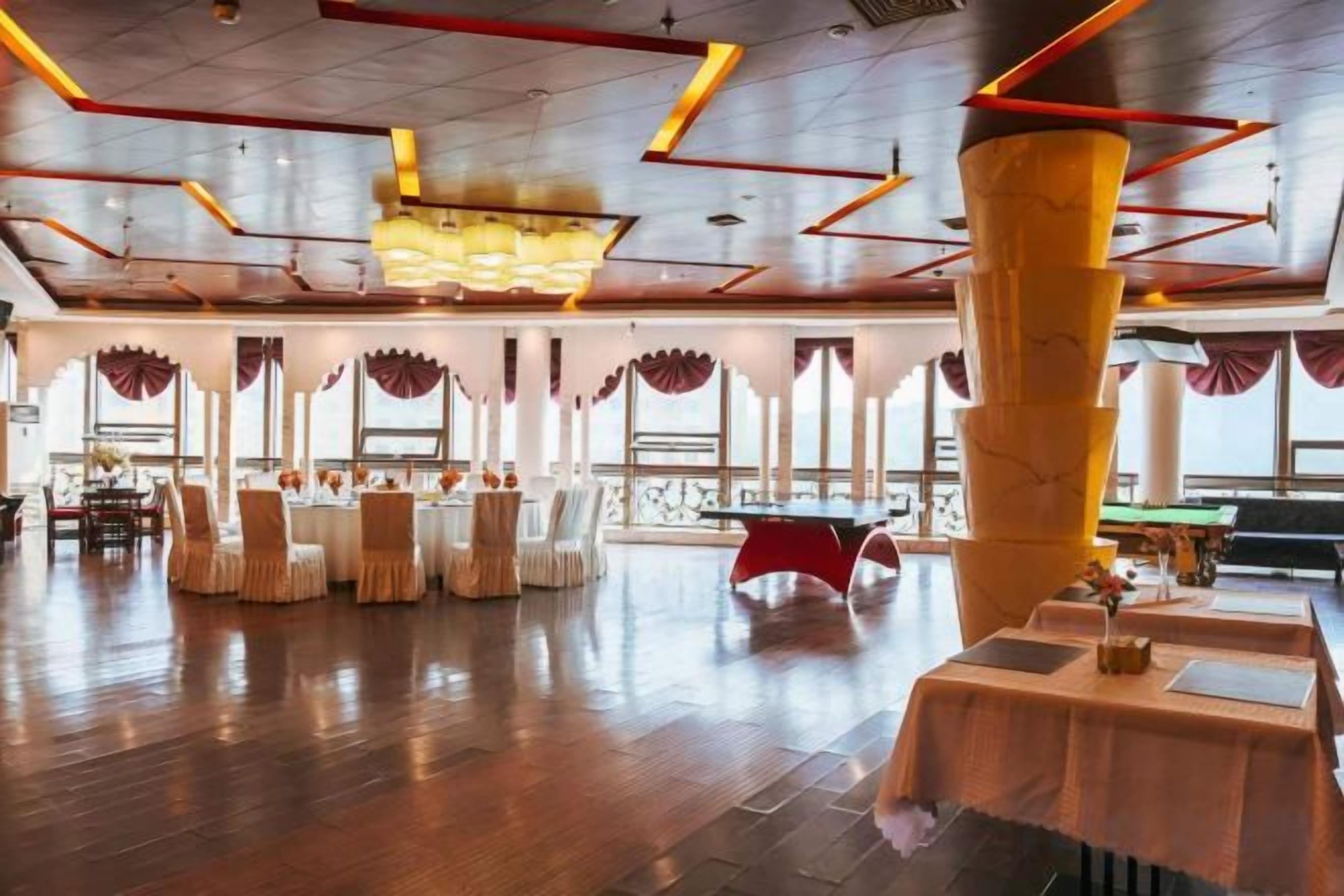A spacious indoor area with a high ceiling, multiple tables, and chairs arranged for dining.