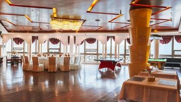A spacious indoor area with a high ceiling, multiple tables, and chairs arranged for dining.