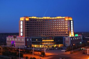Un hotel grande con varios pisos, un atrio central y un estacionamiento.