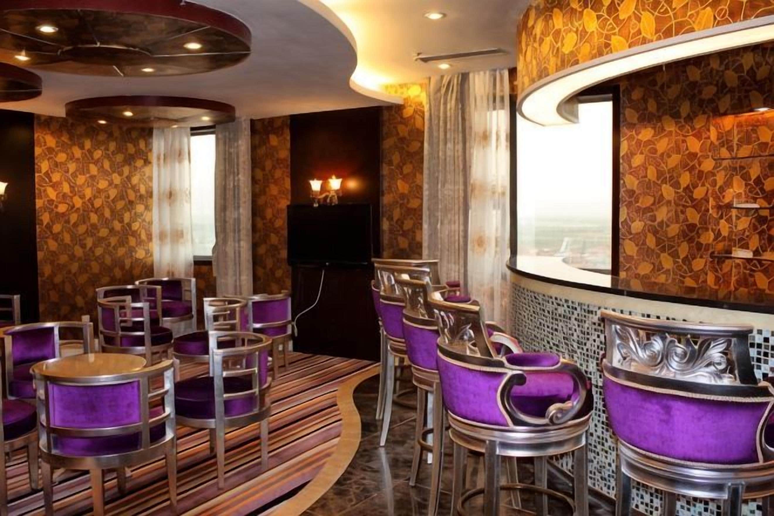 A bar area with purple upholstered chairs and a curved counter.