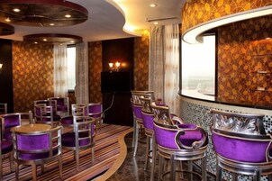 A bar area with purple upholstered chairs and a curved counter.